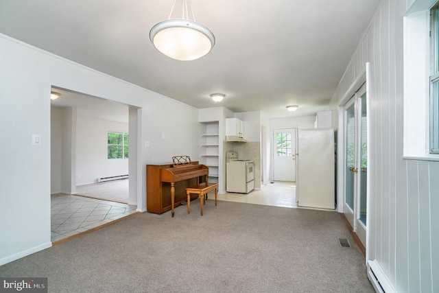 misc room featuring washing machine and clothes dryer, light carpet, and a baseboard heating unit