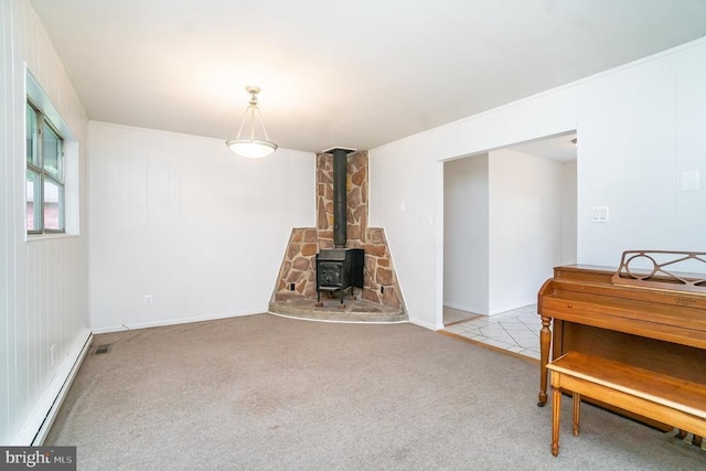 carpeted living room featuring a wood stove and a baseboard heating unit