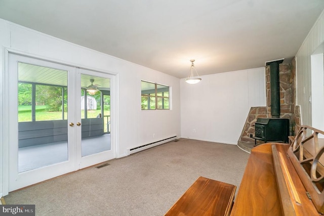 unfurnished living room featuring carpet, a wood stove, baseboard heating, and french doors