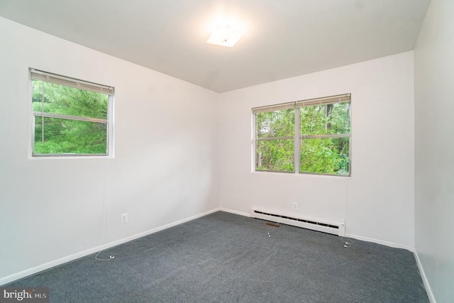 spare room featuring dark carpet and a baseboard heating unit