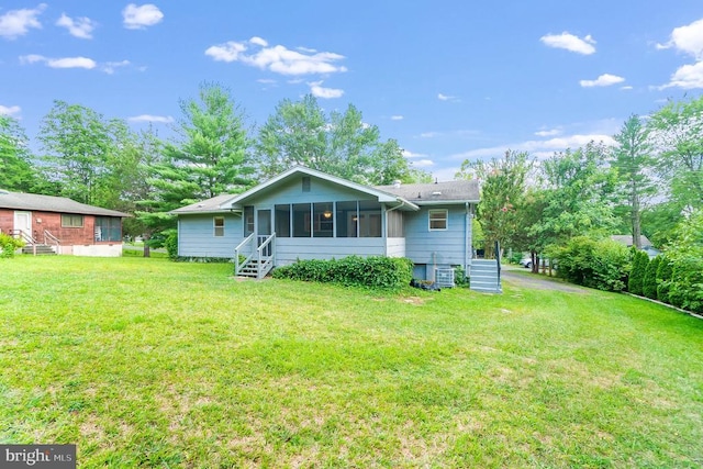 rear view of property with a sunroom and a yard