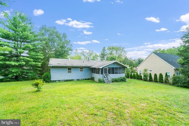 rear view of property featuring a lawn and a sunroom