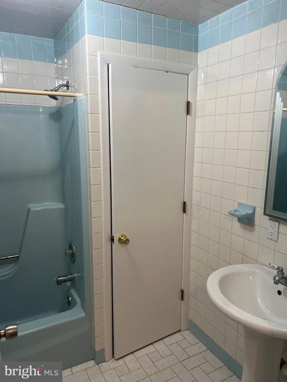 bathroom featuring sink, tile walls, and bathing tub / shower combination