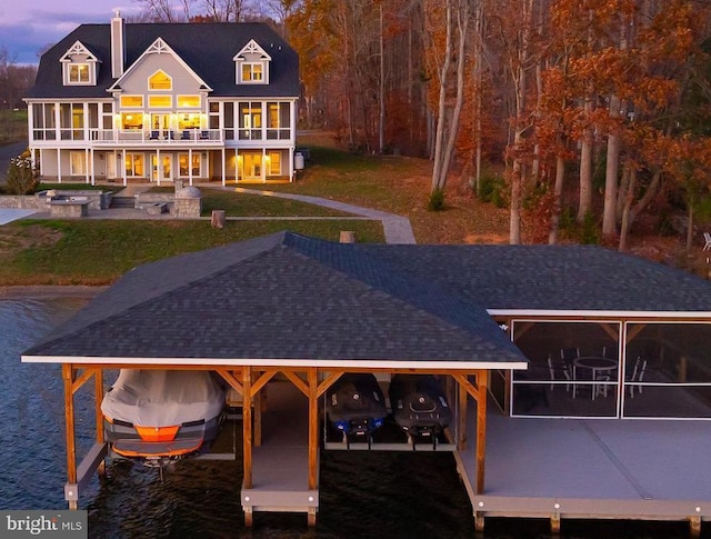 back house at dusk with a water view and a lawn