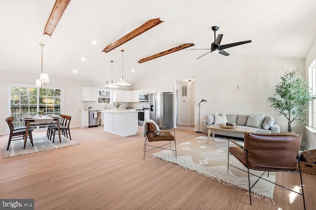 living room with ceiling fan, beamed ceiling, high vaulted ceiling, and light wood-type flooring