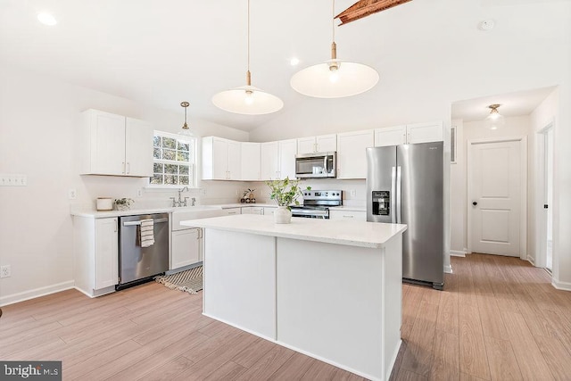 kitchen featuring stainless steel appliances, pendant lighting, light hardwood / wood-style flooring, white cabinets, and a kitchen island