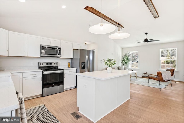 kitchen featuring white cabinetry, ceiling fan, decorative light fixtures, a kitchen island, and appliances with stainless steel finishes