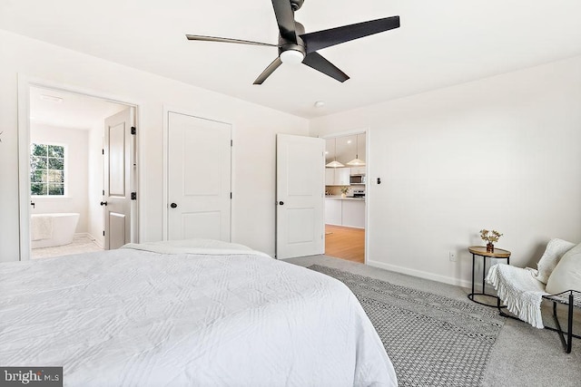 carpeted bedroom with ensuite bathroom and ceiling fan