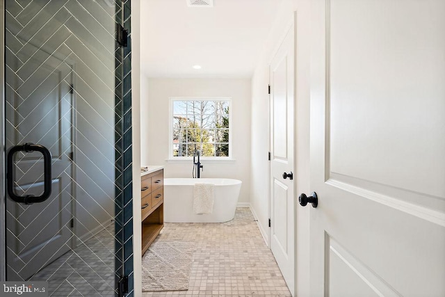 bathroom with a tub to relax in, tile patterned floors, and vanity