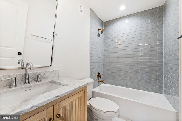 full bathroom with tiled shower / bath, vanity, and toilet