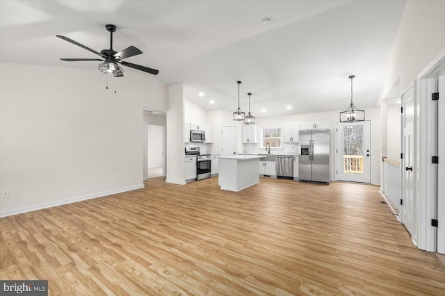 unfurnished living room with light wood-type flooring, ceiling fan with notable chandelier, vaulted ceiling, and sink