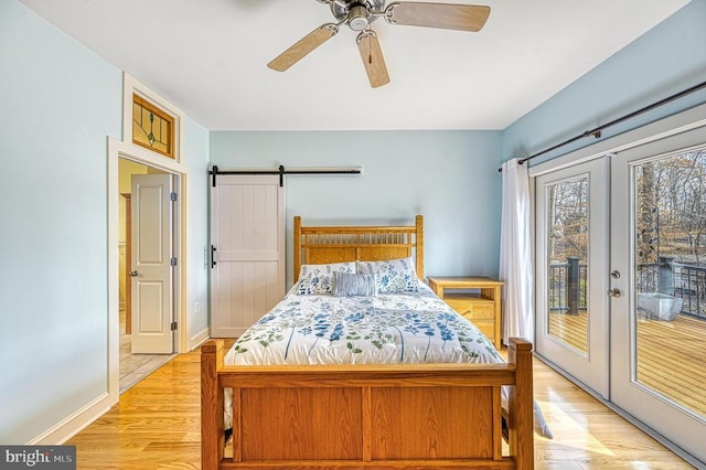 bedroom featuring ceiling fan, french doors, a barn door, light hardwood / wood-style flooring, and access to outside