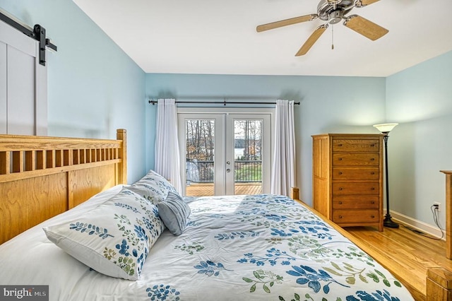 bedroom with access to exterior, ceiling fan, hardwood / wood-style floors, and a barn door