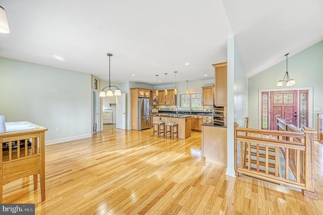 kitchen with a kitchen bar, light wood-type flooring, pendant lighting, a center island, and stainless steel refrigerator