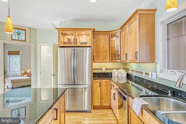 kitchen featuring sink, hanging light fixtures, tasteful backsplash, dark stone counters, and appliances with stainless steel finishes