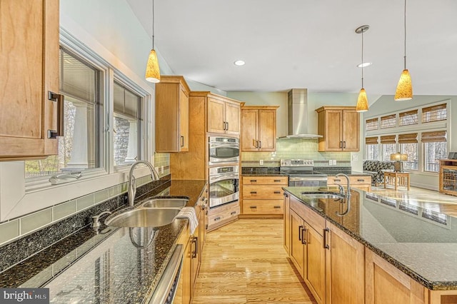 kitchen featuring pendant lighting, stainless steel appliances, wall chimney exhaust hood, and sink