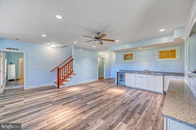 kitchen with hardwood / wood-style floors, white cabinets, wine cooler, ceiling fan, and light stone counters