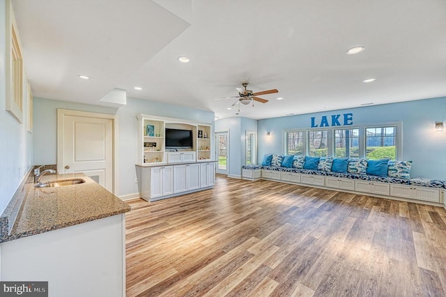 workout area featuring ceiling fan, sink, and light wood-type flooring