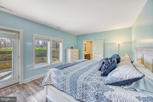 bedroom featuring access to exterior, light wood-type flooring, connected bathroom, and multiple windows