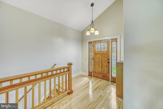 foyer featuring light wood-type flooring, an inviting chandelier, and vaulted ceiling