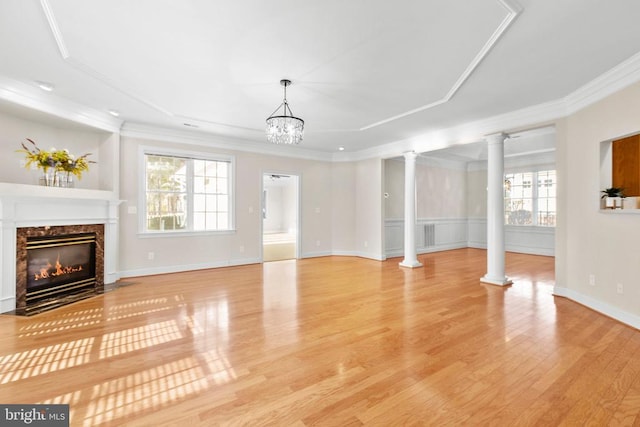 unfurnished living room featuring a high end fireplace, light hardwood / wood-style flooring, an inviting chandelier, and ornamental molding