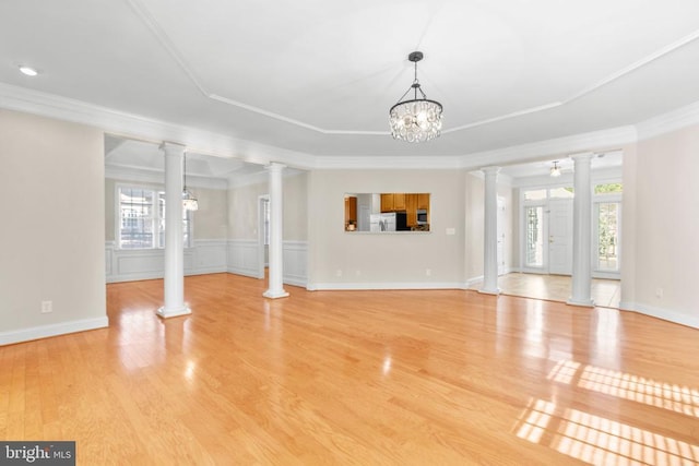 unfurnished living room with light hardwood / wood-style flooring, ornamental molding, and a notable chandelier