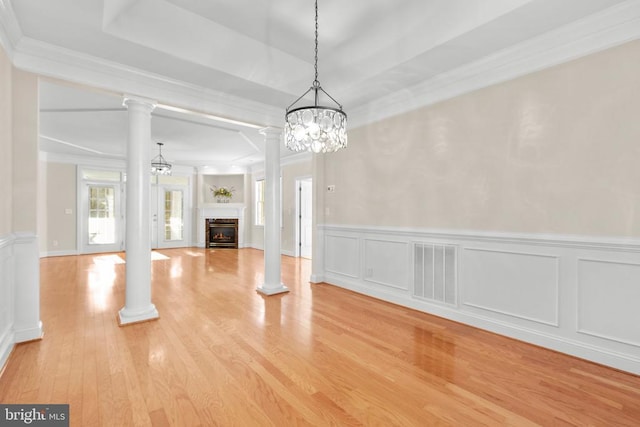 unfurnished living room with light wood-type flooring, crown molding, and a notable chandelier