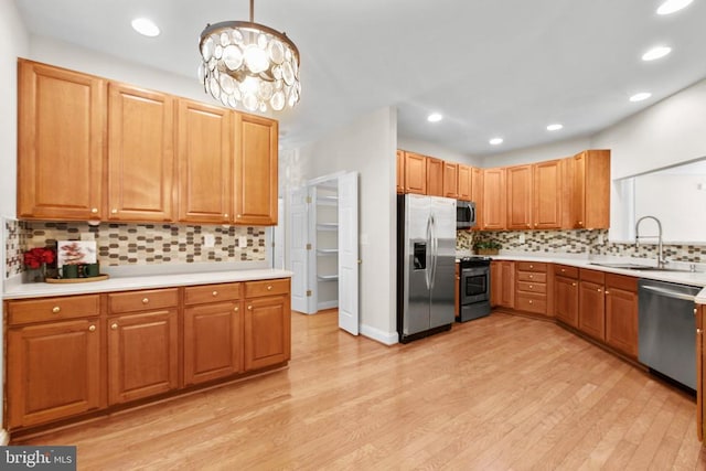 kitchen featuring sink, a chandelier, decorative light fixtures, appliances with stainless steel finishes, and light wood-type flooring