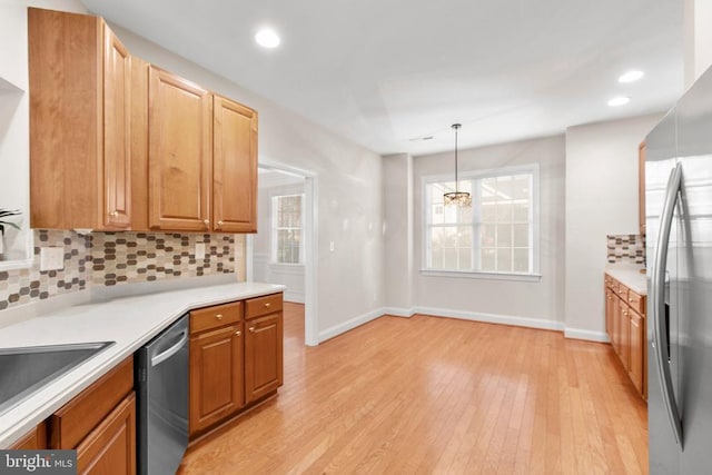 kitchen with decorative light fixtures, decorative backsplash, appliances with stainless steel finishes, a notable chandelier, and light hardwood / wood-style floors