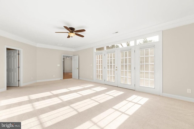 carpeted spare room with ceiling fan, ornamental molding, and french doors