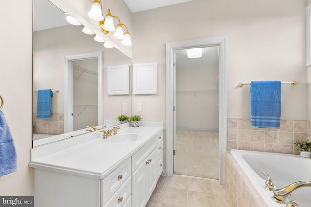 bathroom with tile patterned flooring, vanity, and tiled bath