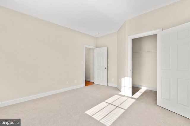 unfurnished bedroom featuring light carpet and a closet