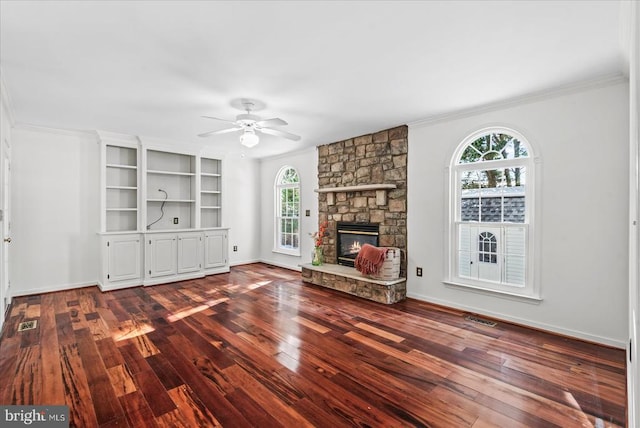 unfurnished living room featuring ceiling fan, a healthy amount of sunlight, a fireplace, and wood-type flooring