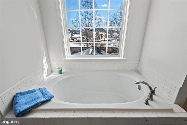 bathroom with tiled tub and plenty of natural light