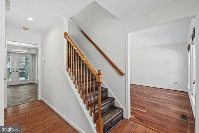 stairs featuring wood-type flooring, french doors, and crown molding