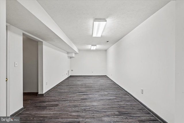 basement with a textured ceiling and dark hardwood / wood-style floors