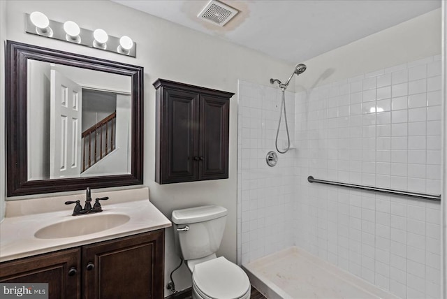 bathroom featuring toilet, tiled shower, and vanity