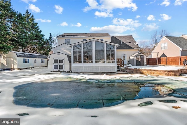 rear view of house featuring a covered pool, a sunroom, a storage shed, and a patio