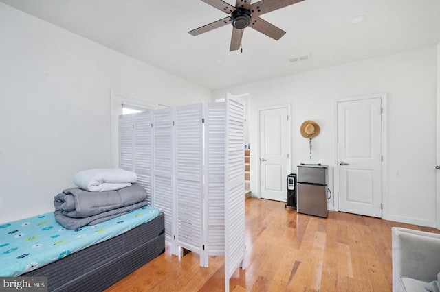 bedroom featuring ceiling fan, stainless steel refrigerator, and light hardwood / wood-style flooring