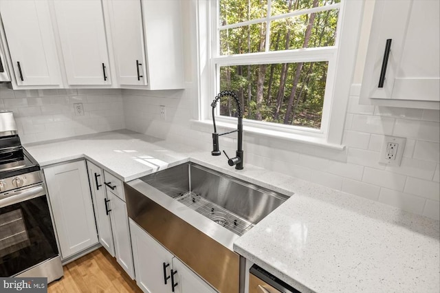 kitchen with white cabinets, stainless steel stove, and light stone countertops