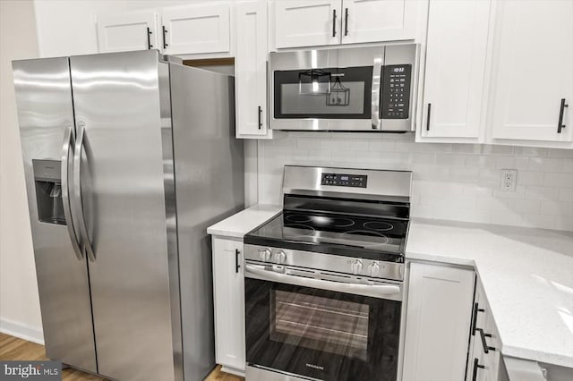 kitchen with tasteful backsplash, light stone counters, white cabinets, and stainless steel appliances