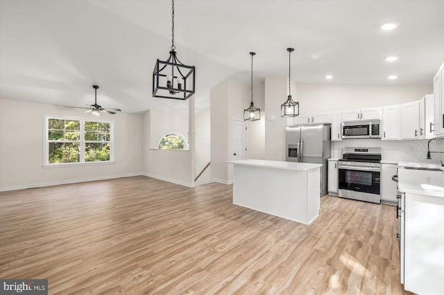 kitchen with hanging light fixtures, ceiling fan, appliances with stainless steel finishes, a kitchen island, and white cabinetry