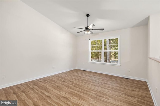 empty room featuring ceiling fan, light wood-type flooring, and vaulted ceiling