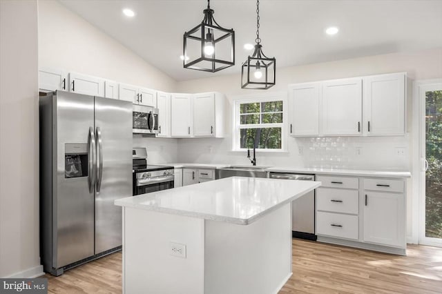 kitchen with white cabinetry, a center island, stainless steel appliances, pendant lighting, and lofted ceiling