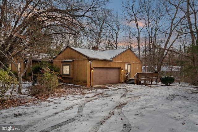 view of snow covered exterior with a wooden deck and a garage