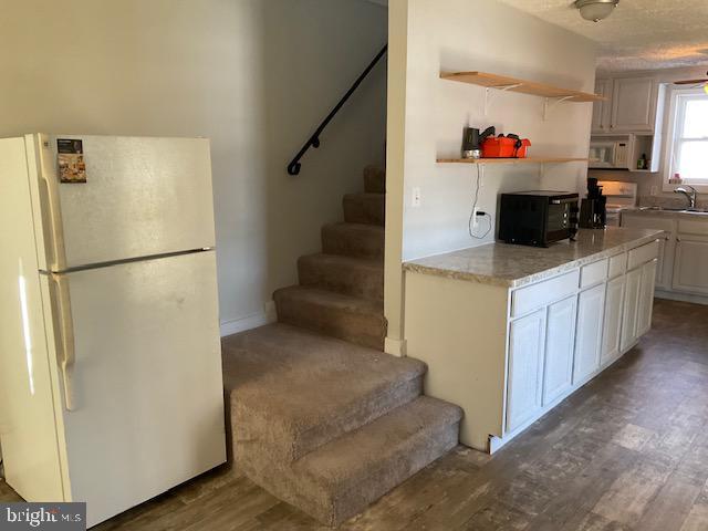 kitchen with white appliances, white cabinets, hardwood / wood-style floors, and sink