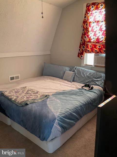 bedroom with lofted ceiling, cooling unit, and carpet flooring