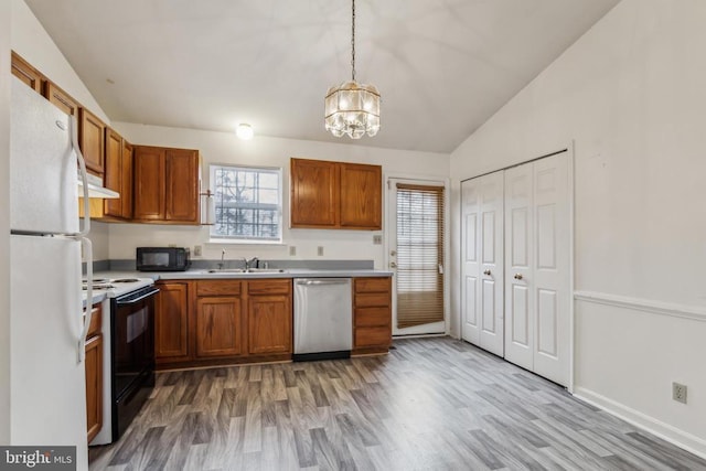 kitchen featuring pendant lighting, black appliances, sink, light hardwood / wood-style flooring, and a notable chandelier