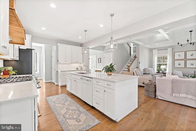 kitchen featuring pendant lighting, white dishwasher, an island with sink, beamed ceiling, and white cabinetry