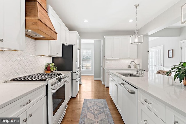 kitchen with premium range hood, white cabinets, sink, dishwasher, and high end white range